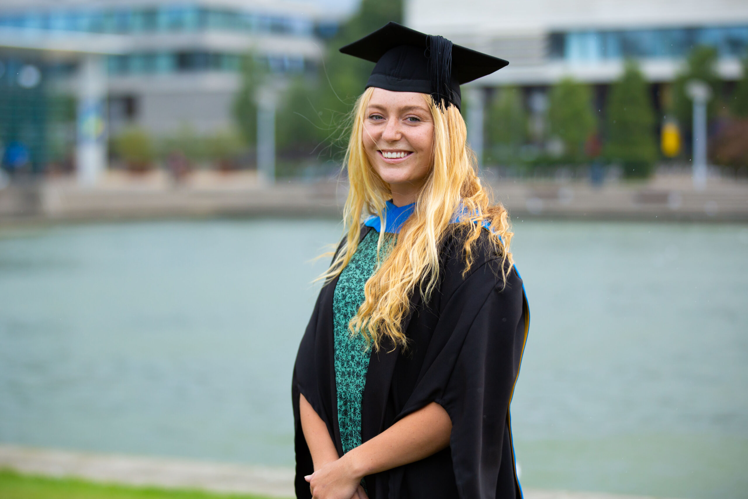 Lara poses in front of the UCD lake in her graduation cap and gown.